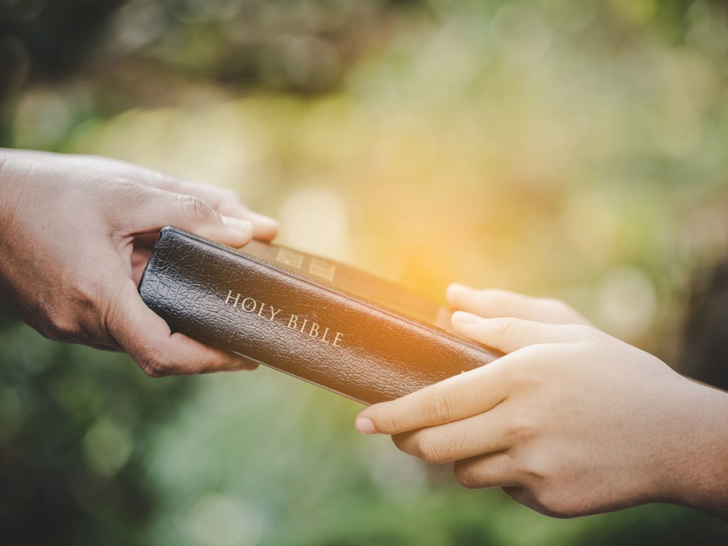 man giving person a Bible | evangelism resources