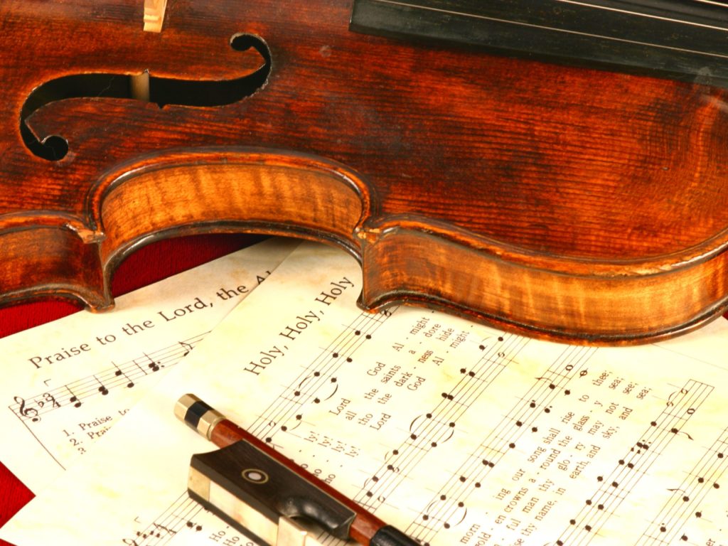 A violin, bow, and sheet music of hymns | Music ministry